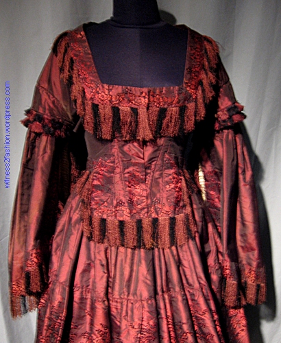 Front detail of bodice showing long, square front and fringe trim.